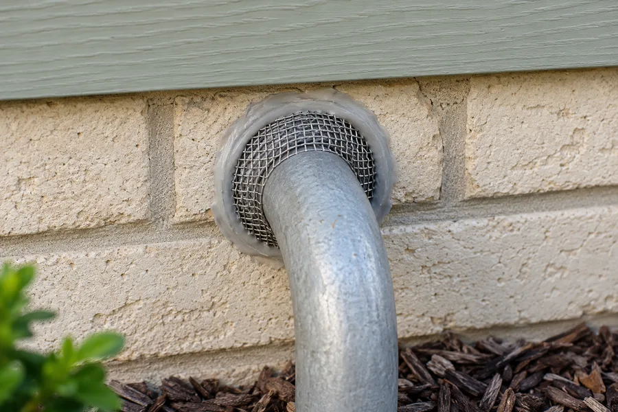 Metal mesh and sealant closing a gap around an exterior utility pipe